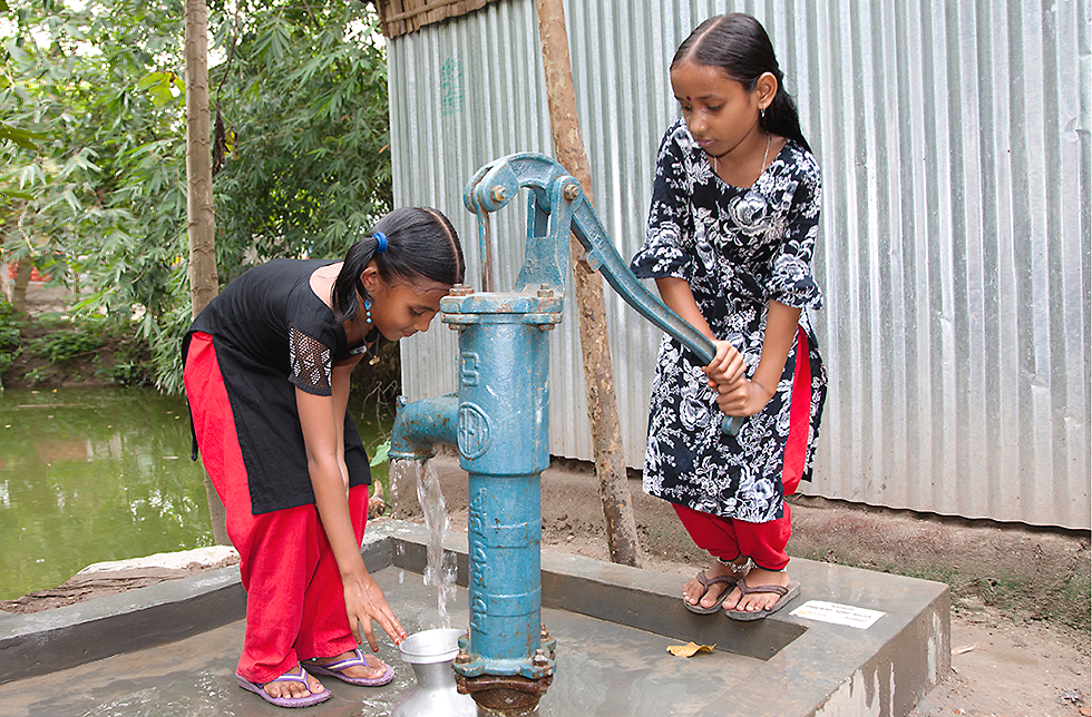 Zwei Mädchen schöpfen sauberes Wasser bei Brunnen in Bangladesch