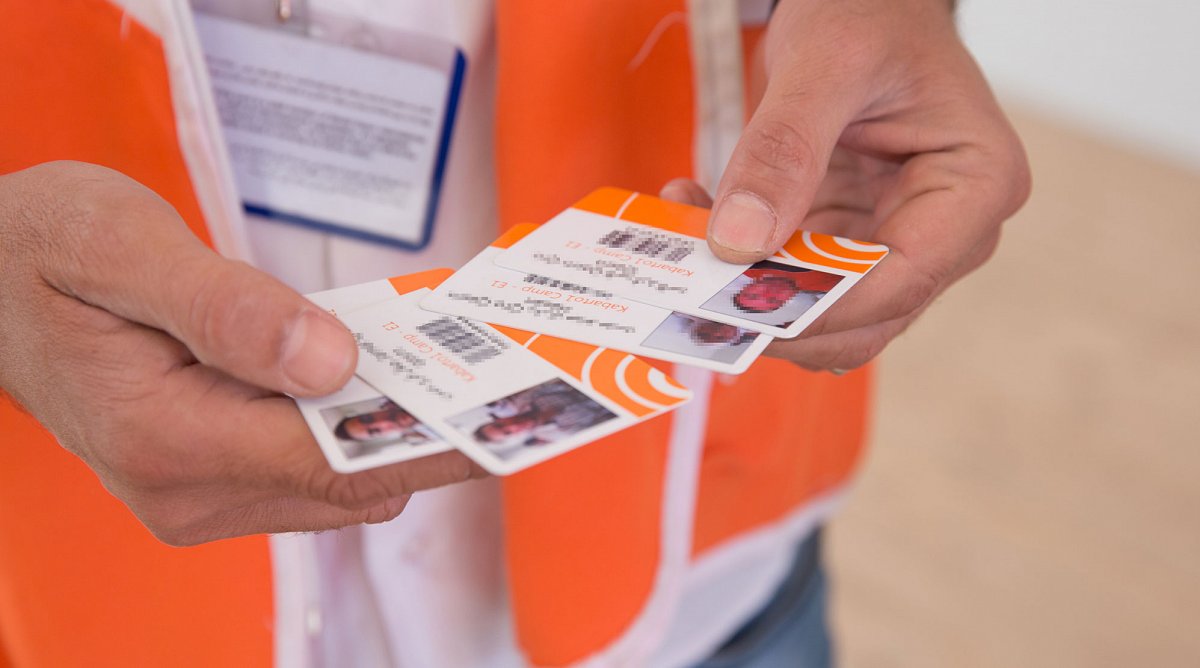 Ein Mitarbeiter von World Vision hält Identitätskarten für eine Verteilaktion von Hilfsgütern in den Händen.