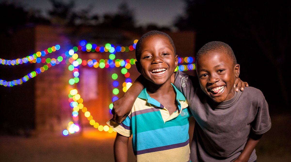 Sambia: Zwei Jungen freuen sich über Weihnachtsbeleuchtung.