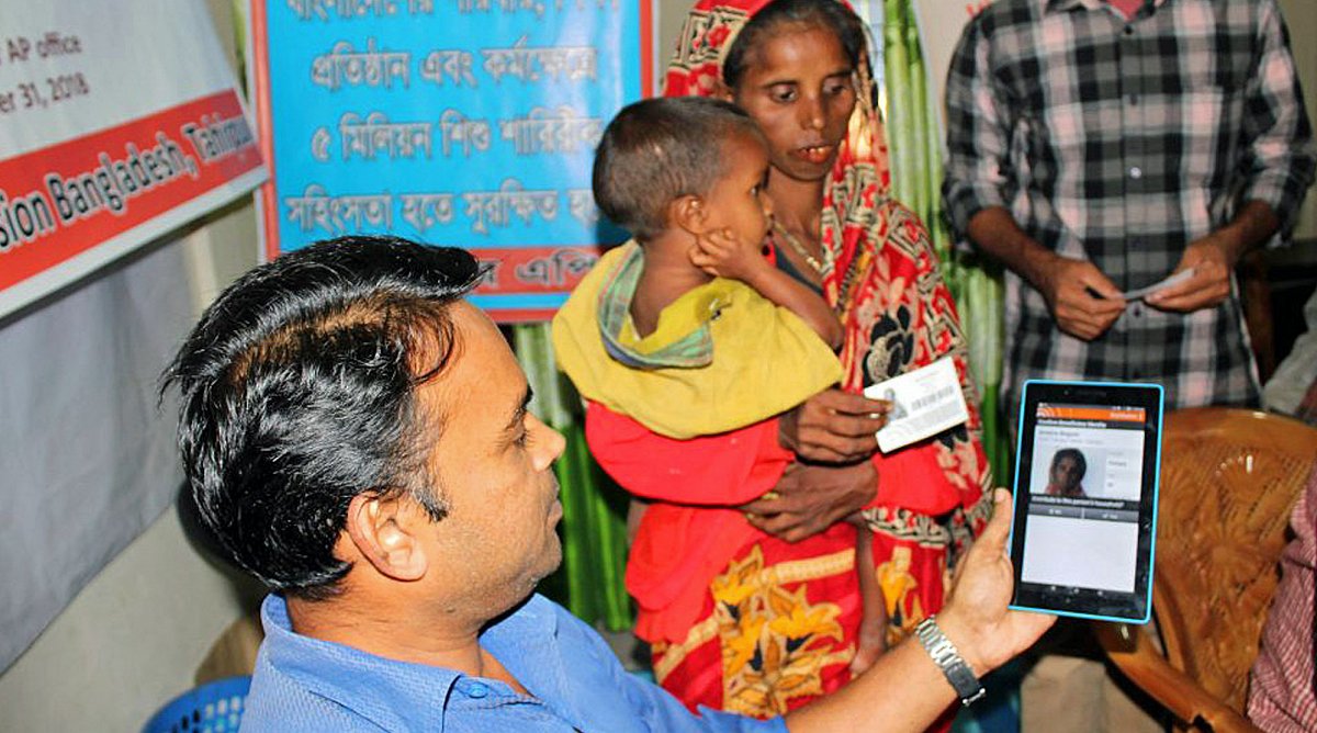 Ein World Vision-Mitarbeiter scannt mit einem Tablet die Nothilfe-Karte einer Familie.