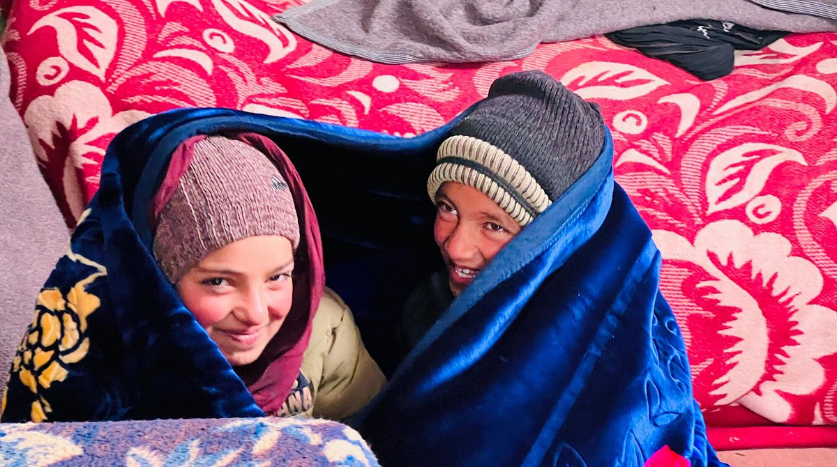 Afghanistan : Deux enfants sont enveloppés dans une couverture.