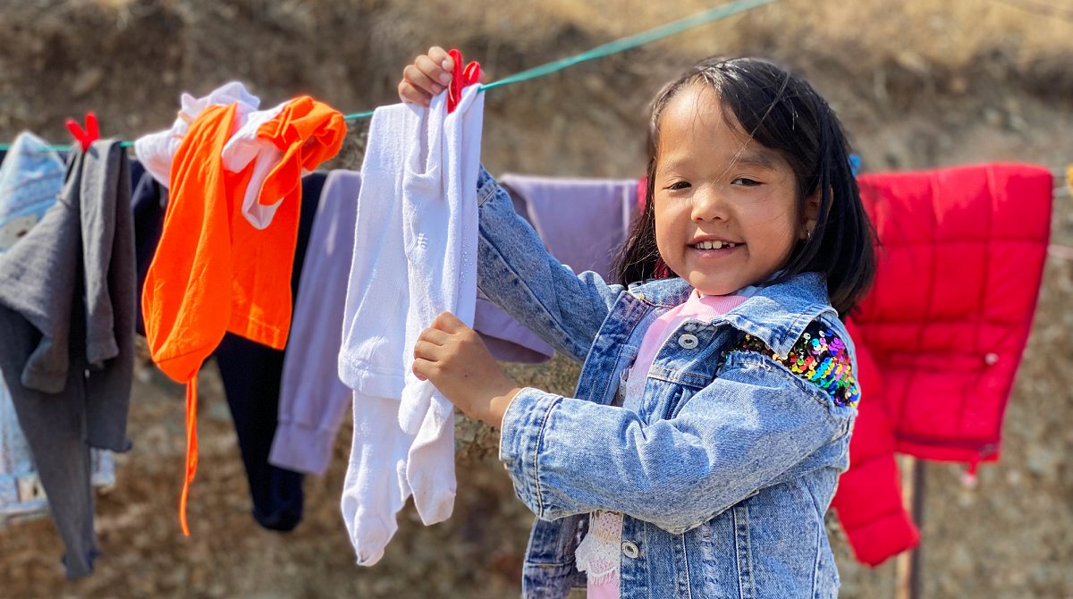 Mongolei: Ein Mädchen hängt frisch gewaschene Kleider an einer Wäscheleine auf.