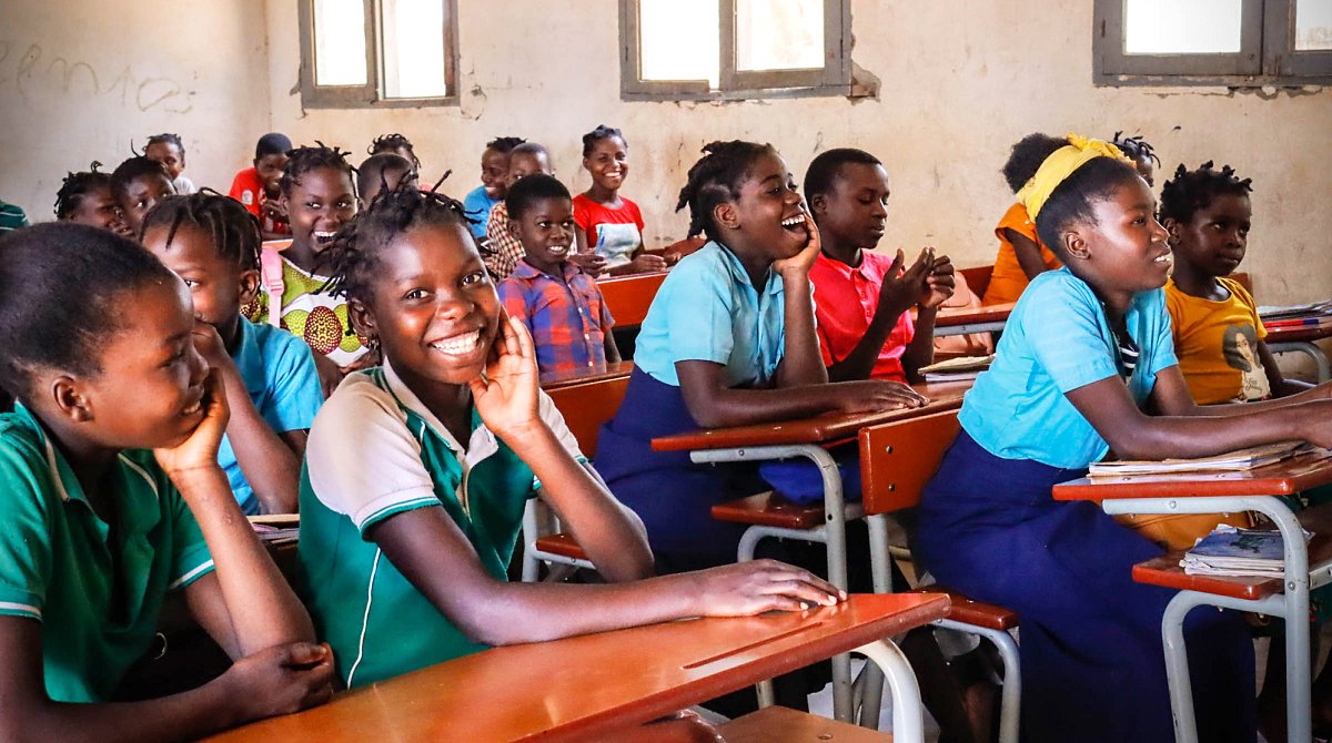 Schulkinder in Mosambik sitzen fröhlich in ihrem Klassenzimmer
