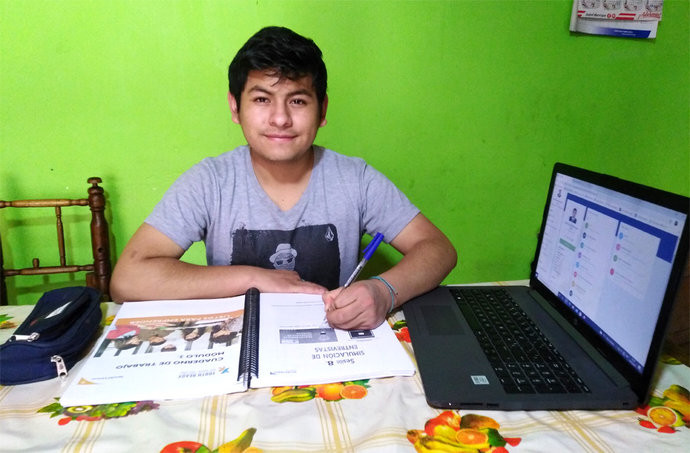 Peru: Ein junger Mann sitzt hinter seinen Studienunterlagen