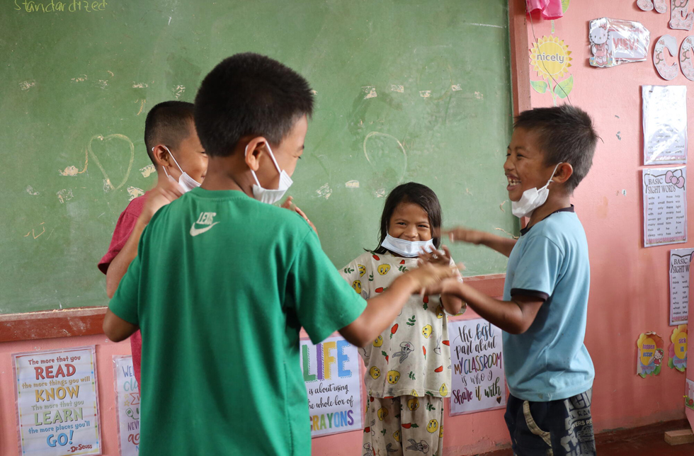 Philippinen: Vier Kinder spielen in einem Schulzimmer.