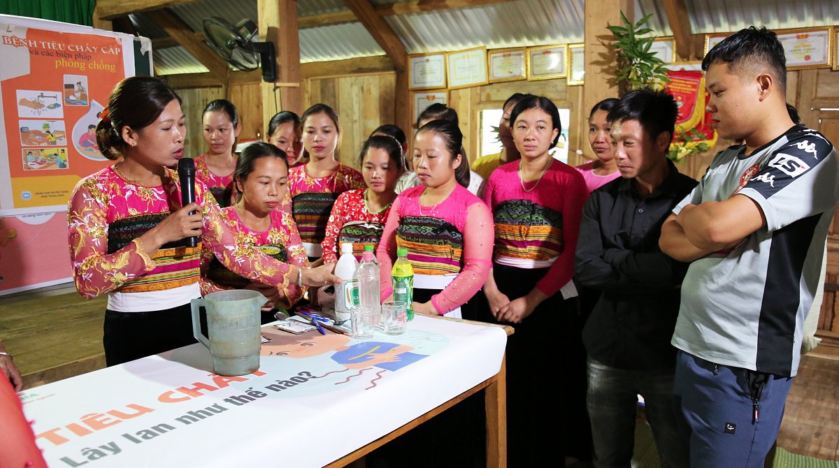 Vietnam: Die Teilnehmenden eines World Vision-Ernährungsclubs stehen um einen Tisch und die Kursleiterin herum.