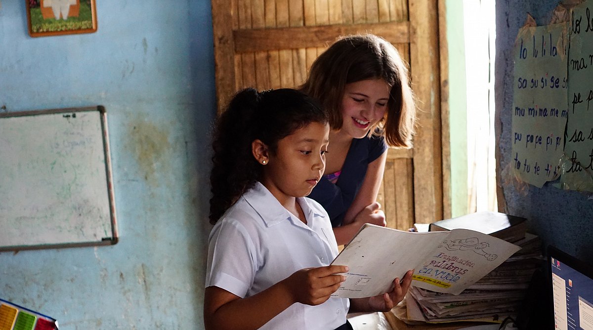 Emma Schweiger liest ein Schulbuch mit Schülerin in Nicaragua