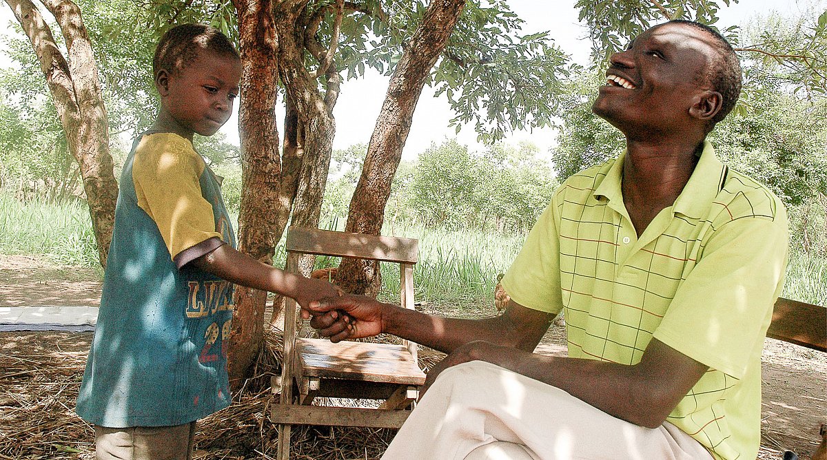 Mann hält Kind an der Hand in Uganda.