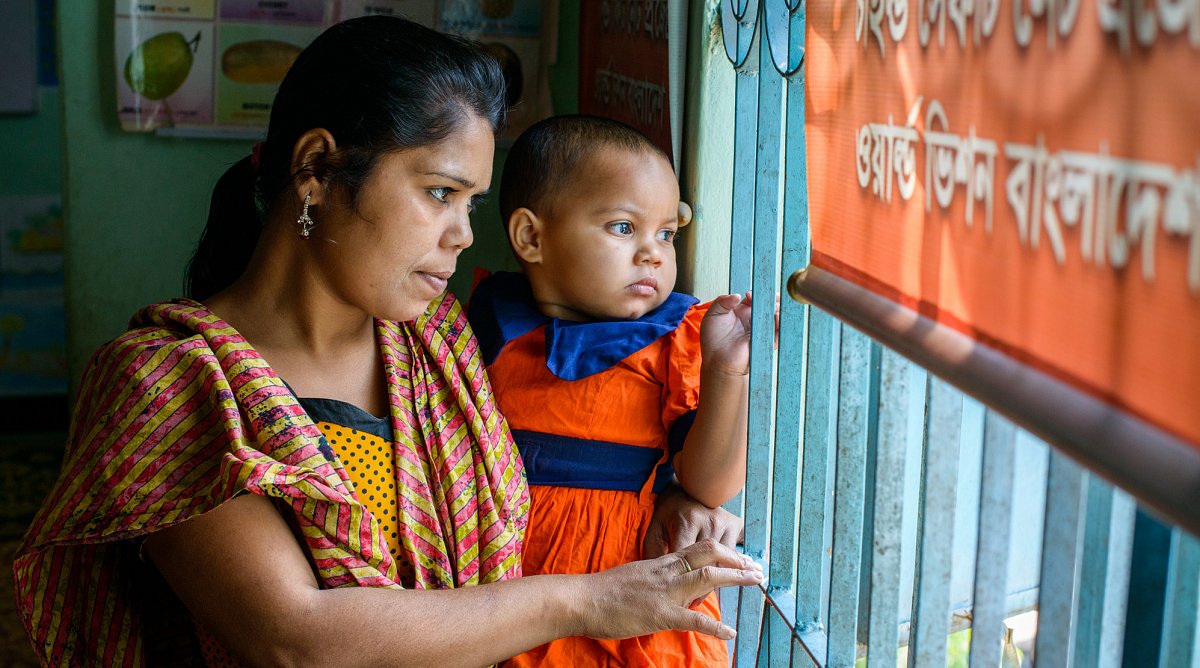 Eine Mutter schaut mit ihrem Kind aus dem Fenster ihres Wohn- und Arbeitszimmers: Einem Bordell in Jessore, Bangladesch.