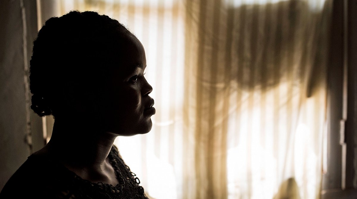 Demokratische Republik Kongo/DRK/DRC: Das Profil einer Frau, die vor einem hellen Fenster mit hellen Vorhängen steht.