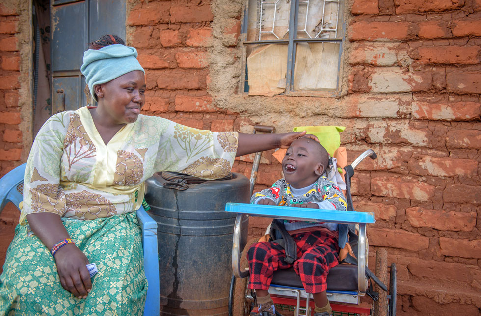 Kenia: Eine Mutter streicht ihrem Sohn, der in einem Rollstuhl sitzt, liebevoll über den Kopf.