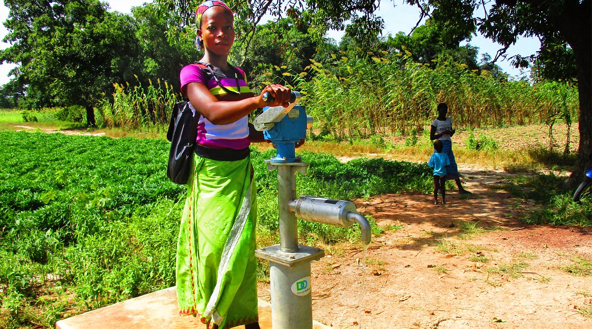 Mädchen pumpt frisches Wasser aus Brunnen.