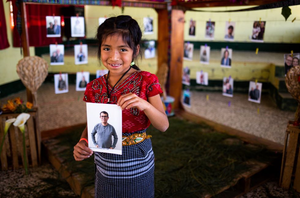 Ein junges achtjähriges Mädchen hält das Foto eines Mannes in der Hand und lächelt in die Kamera