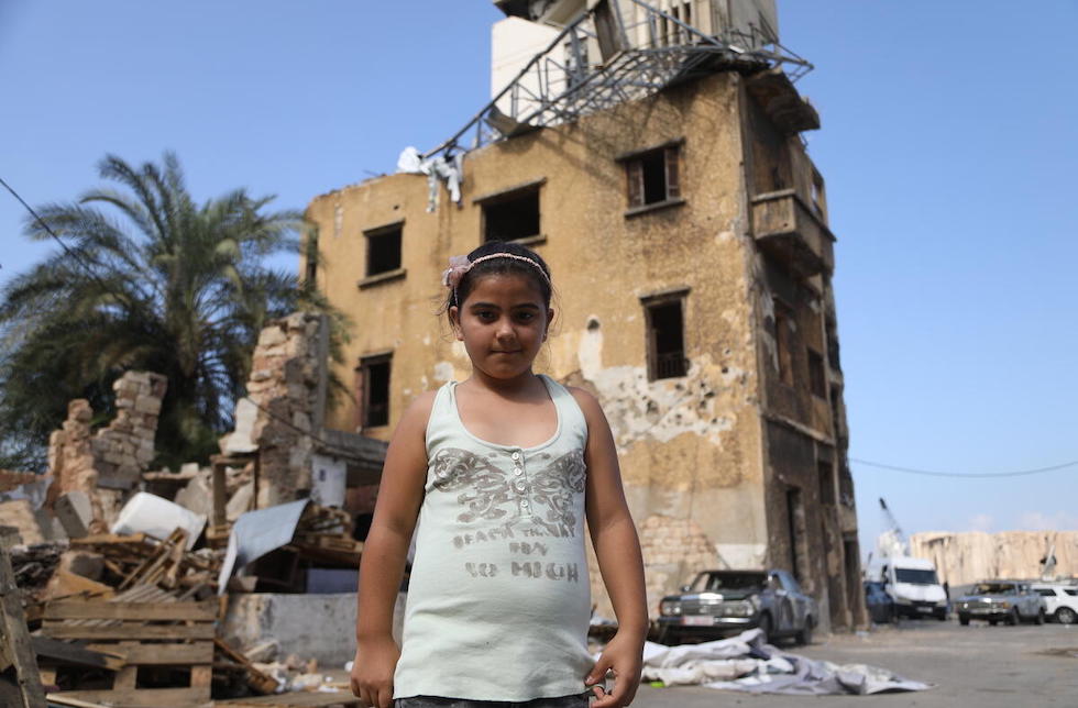 Ein Mädchen steht vor einem zerstörten Haus im Libanon.