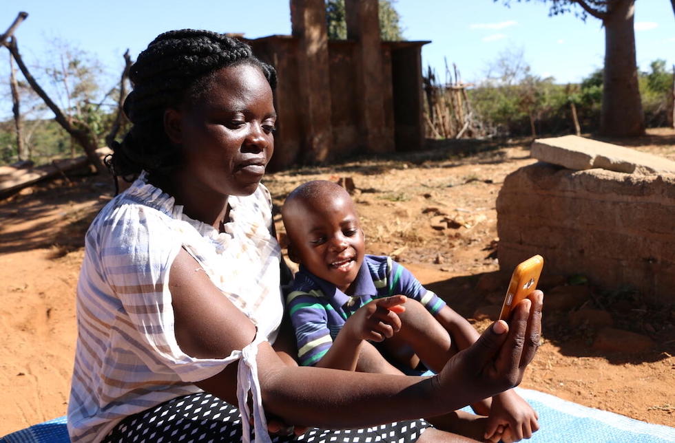 Simbabwe: Eine Mutter schaut mit ihrem Sohn auf ein Smartphone, sie lernen. 