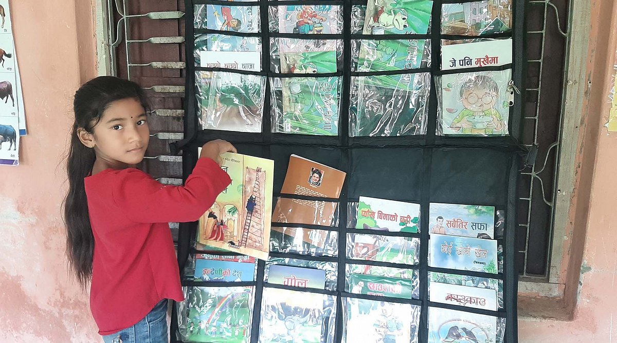 Nepal: Mädchen wählt ein Buch zum Lesen aus.
