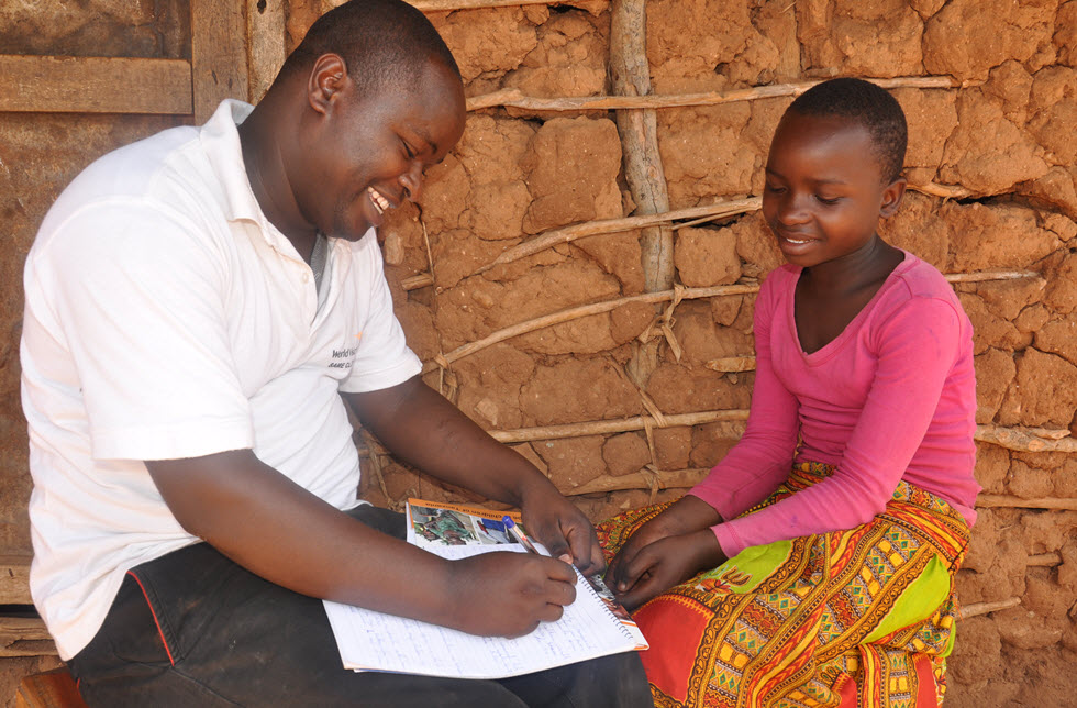 Ein Mädchen  mit einem World Vision Mitarbeiter in Ruvu Muungano, Tansania - World Vision Schweiz