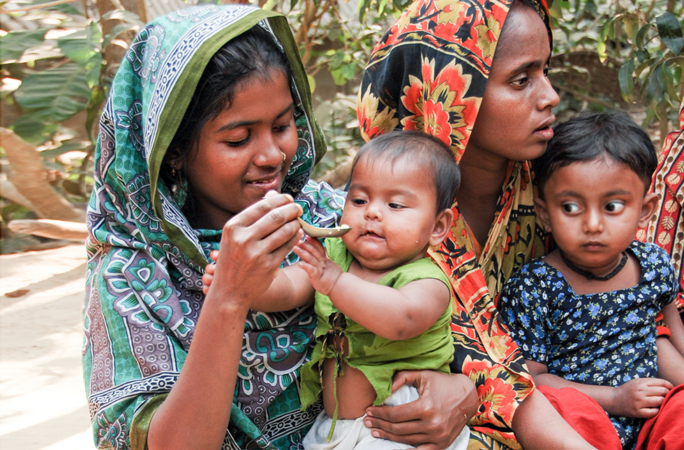 Zwei Mütter mit ihren Kindern bei einem ausgewogenen Essen in Ghoraghat, Bangladesch