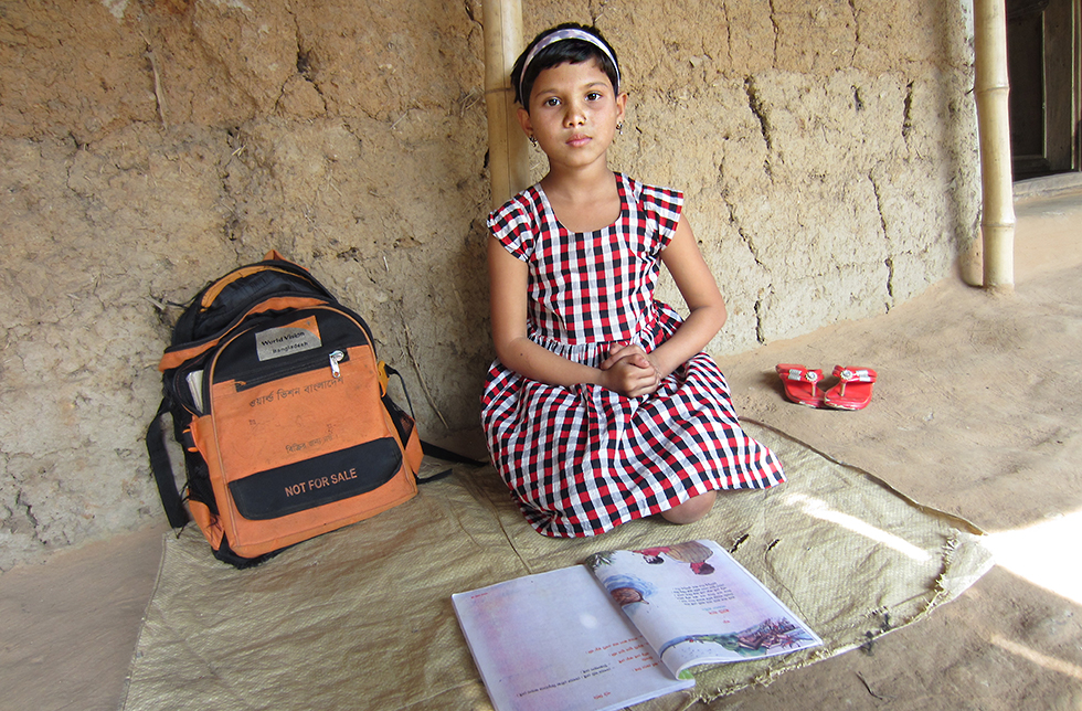 Ein Mädchen liest in einem Schulbuch in Ghoraghat, Bangladesch