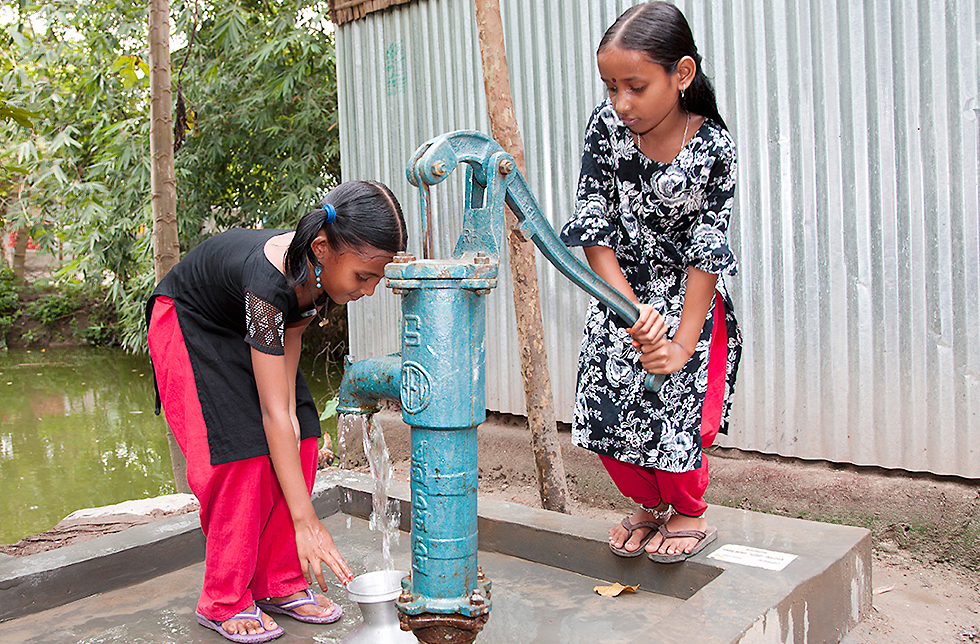 Zwei Mädchen schöpfen sauberes Trinkwasser aus einem Brunnen in Ghoraghat, Bangladesch