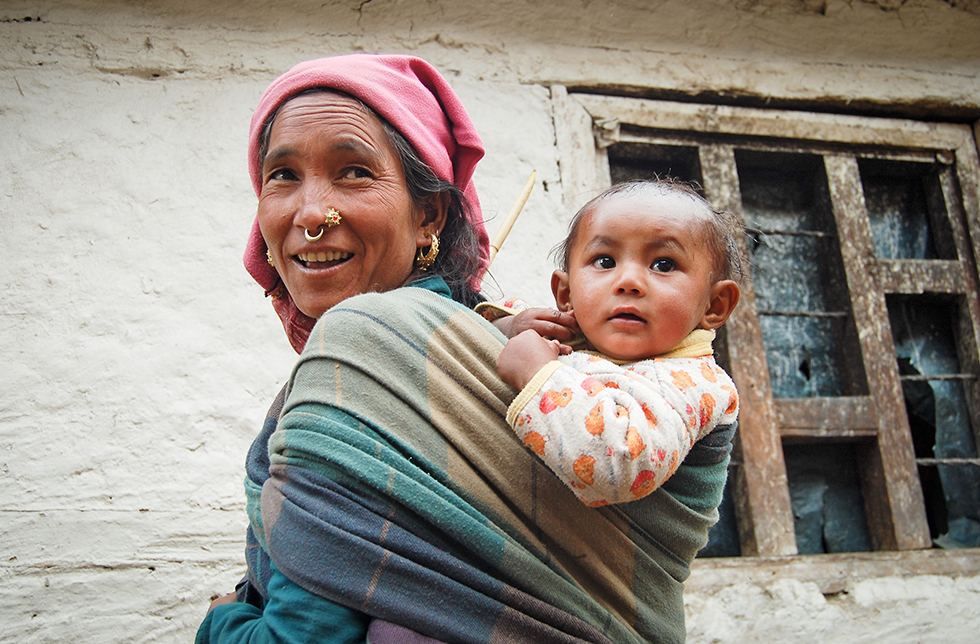 Eine Mutter trägt ihr Kind auf dem Rücken in Jumla-Sinja, Nepal