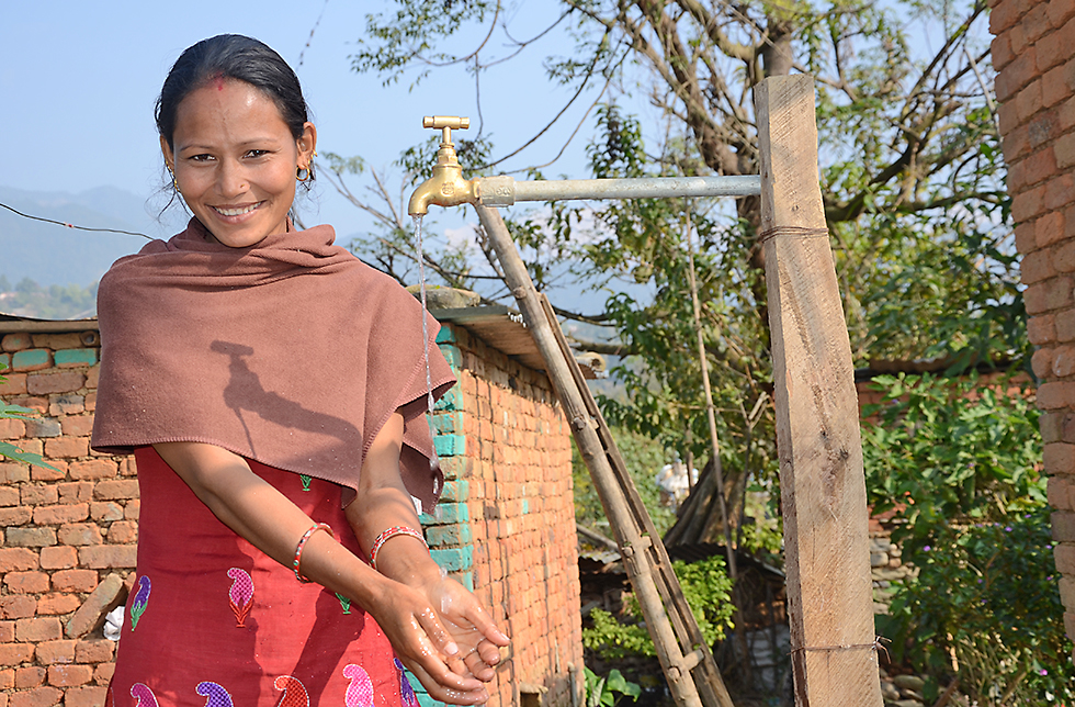 Eine junge Frau wäscht sich die Hände in Lamjung, Nepal