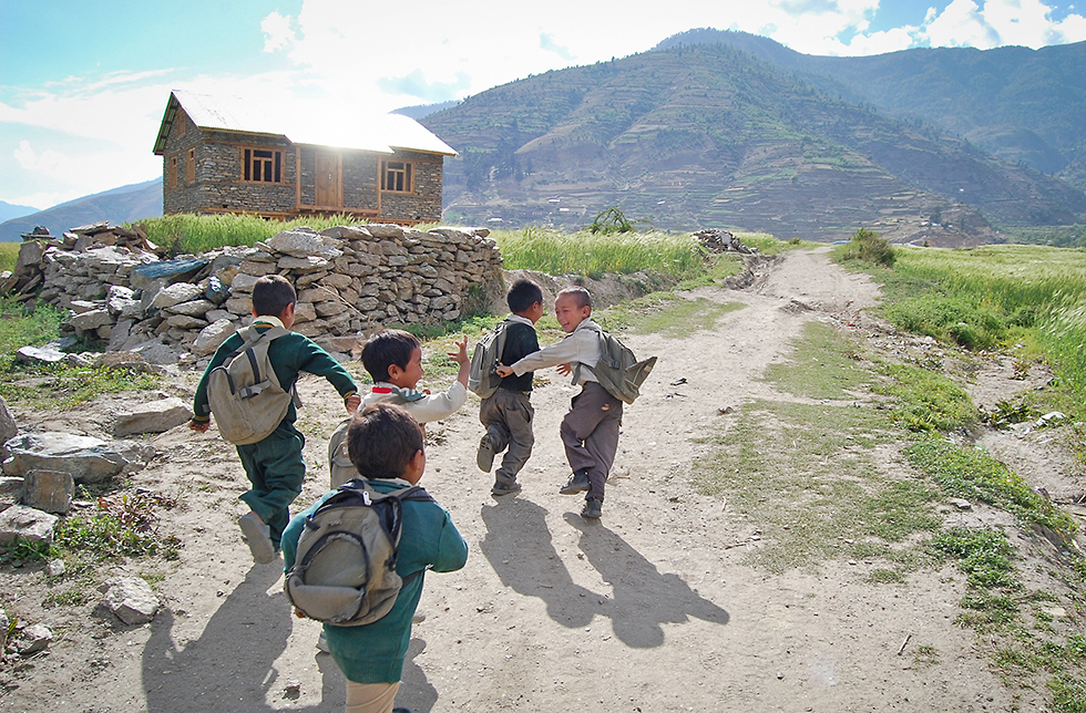 Schulkinder rennen auf einer Landstrasse in Lamjung, Nepal