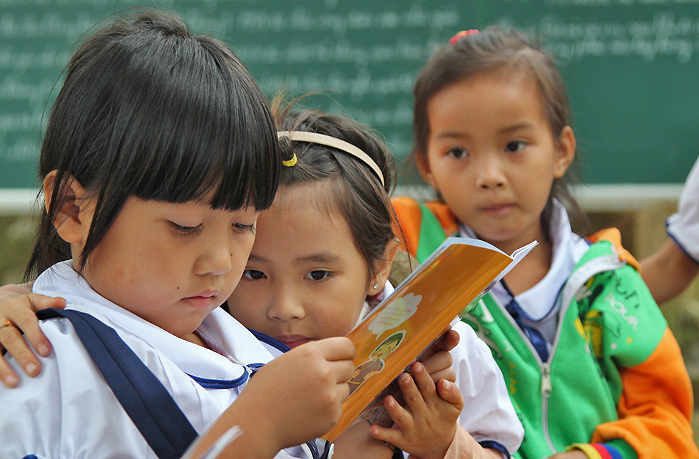 Ein Kind liest in einem Buch in Lang Chanh, Vietnam