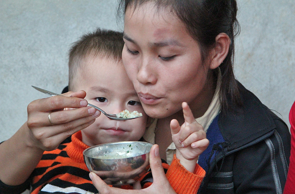 Eine Mutter füttert ihr Kind mit gesunder Nahrung  in Lang Chanh, Vietnam