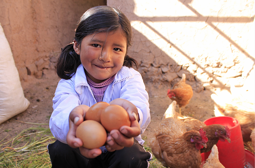 Ein Mädchen zeigt die Eier, die einen wichtigen Bestandteil ihrer ausgewogenen Ernährung darstellen in Sumaj Muju, Bolivien