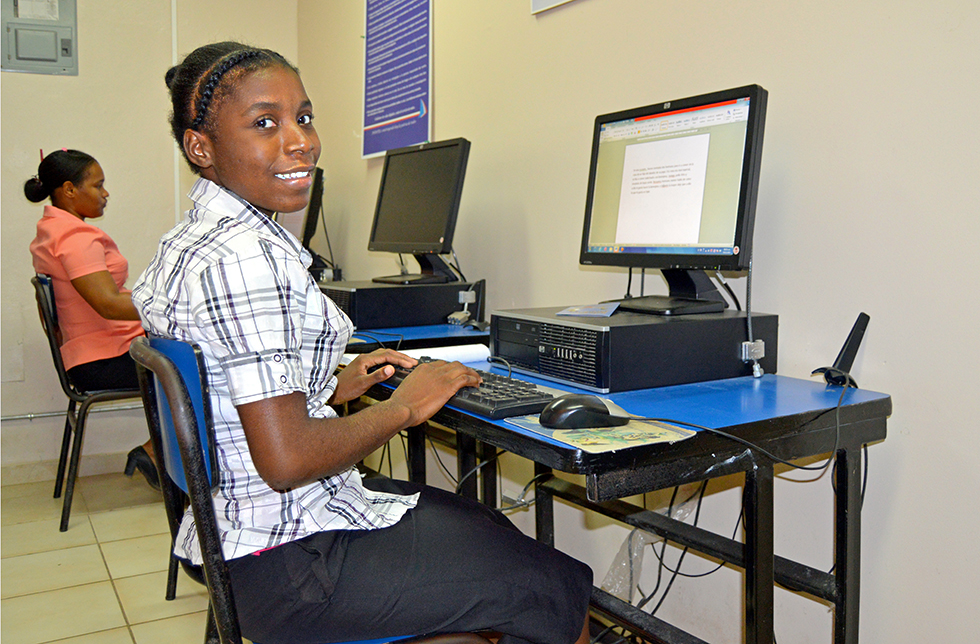 Ein Mädchen schreibt am Computer in Canaan, dominikanische Republik 