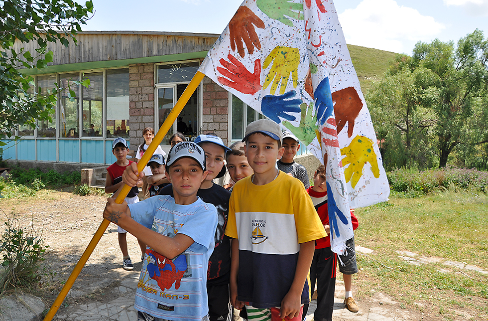 Eine Gruppe von Schulkindern mit einer selbst gemalten Fahne in Kapan, Armenien 