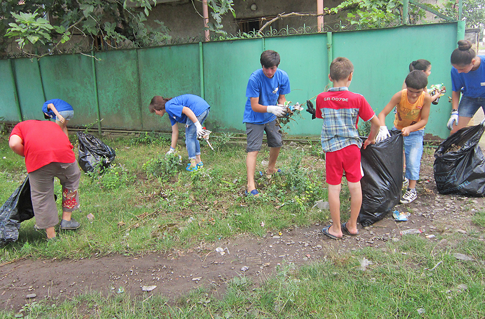 Kinder helfen Abfall von einer Wiese zu entfernen in Imereti, Georgien