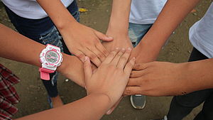 Sechs Kinder legen ihre Hände aufeinander.