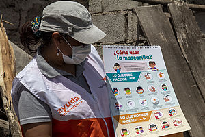 Eine Frau erklärt in Ecuador den Gebrauch von Masken zum Schutz vor Covid-19.