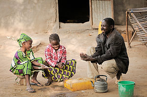 Ein Mann und zwei Mädchen waschen sich die Hände in Mali.