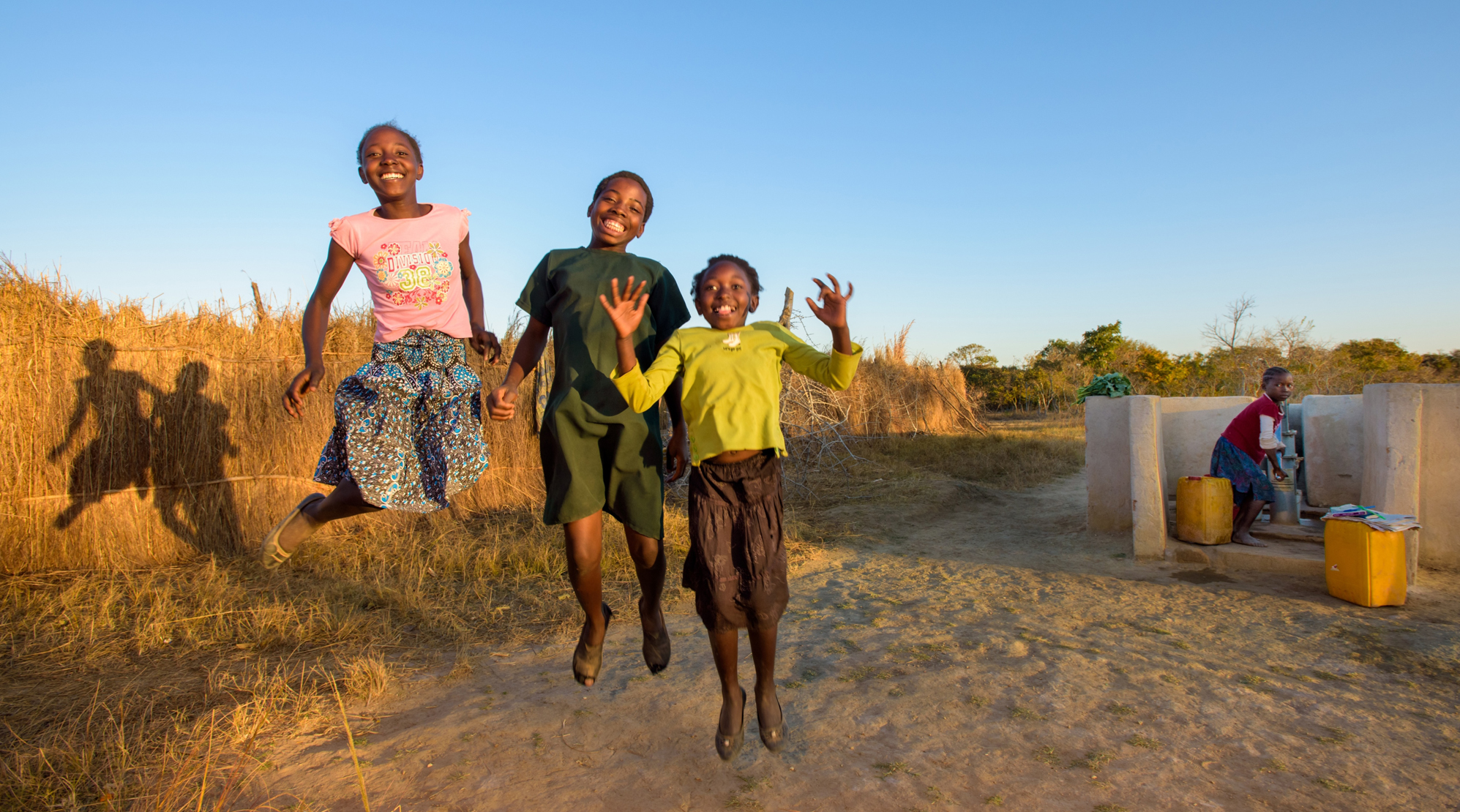 Kinder in Sambia freuen sich über ein Wasserloch.