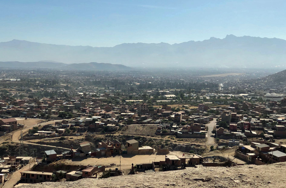 Bolivien: Eine Slum-Siedlung aus einfachen Hütten, die bis zum Horizont reicht. Im Hintergrund hohe Berge 