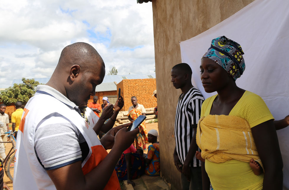 Burundi: Ein Mitarbeiter von World Vision nimmt die Personalien einer bedürftigen Frau mit ihrem Kind auf.