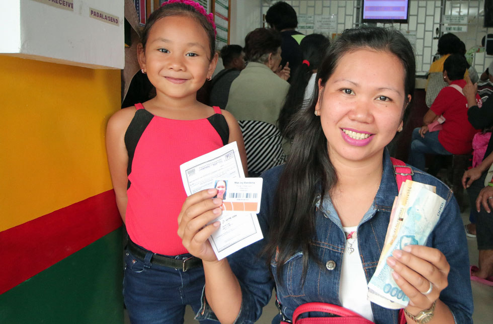 Philippinen: Eine Mutter und ihr Kind zeigen strahlen das Bargeld, dass sie bei der Verteilaktion von World Vision erhalten haben.