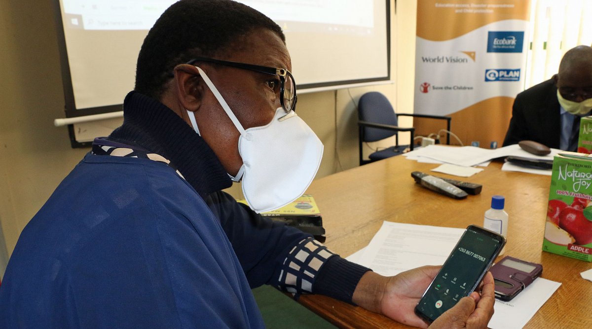 Simbabwe: Eine Frau mit Mundschutz bedient ein Lernprogramm auf ihrem Mobiltelefon.