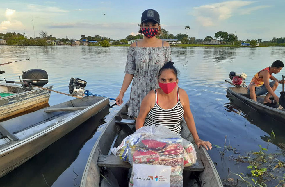 Amazonien, Brasilien: Zwei Frauen transportieren Hilfsgüter über einen Fluss.
