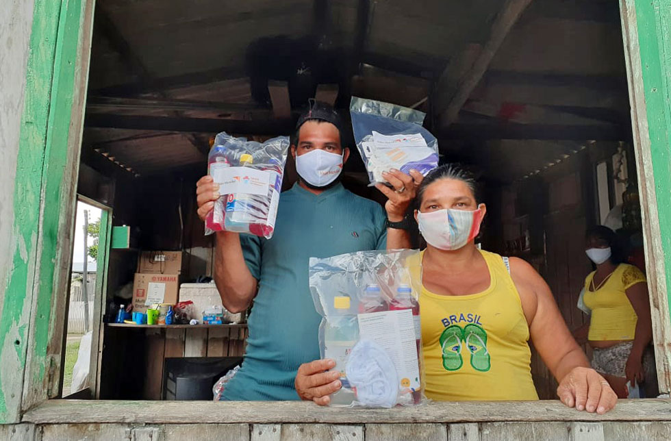 Amazonien, Brasilien: Ein Ehepaar hält erhaltene Hygienekits in den Händen. Sie tragen einen Mundschutz.