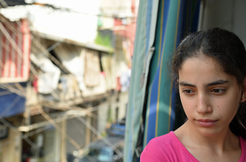 Beirut, Libanon: Ein Mädchen sitzt am Fenster. Hinter ihr die zerstörten Strassen Beiruts.