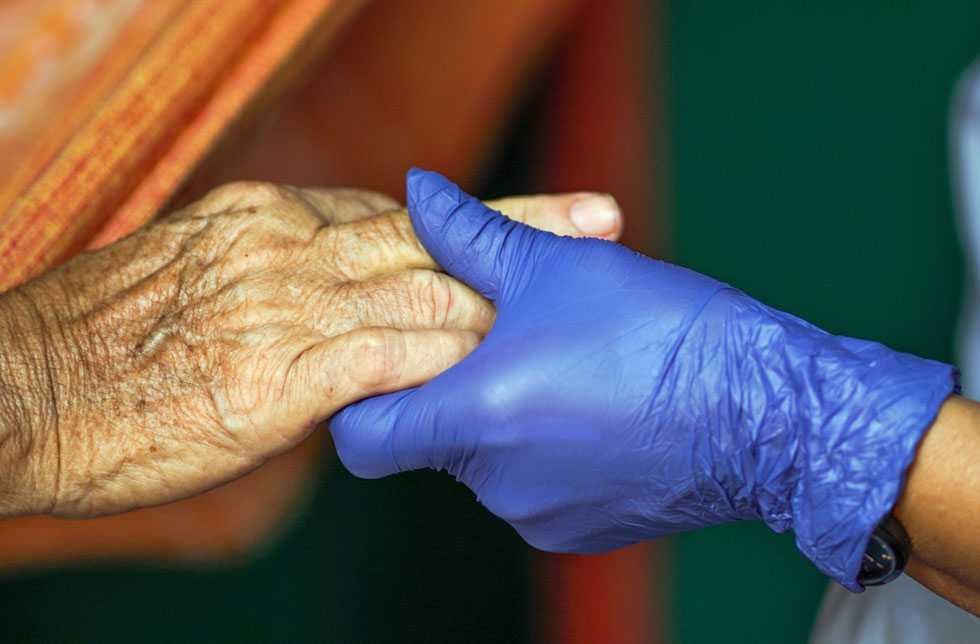 Amazonien, Brasilien: Die Hand einer älteren Frau hält die Hand einer behandschuhten Hand.