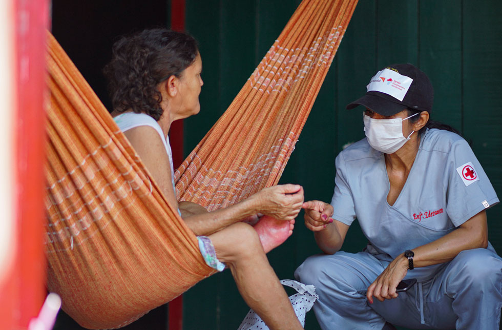 Amazonien, Brasilien: Eine Gesundheitshelferin spricht mit einer Frau in einer Hängematte.