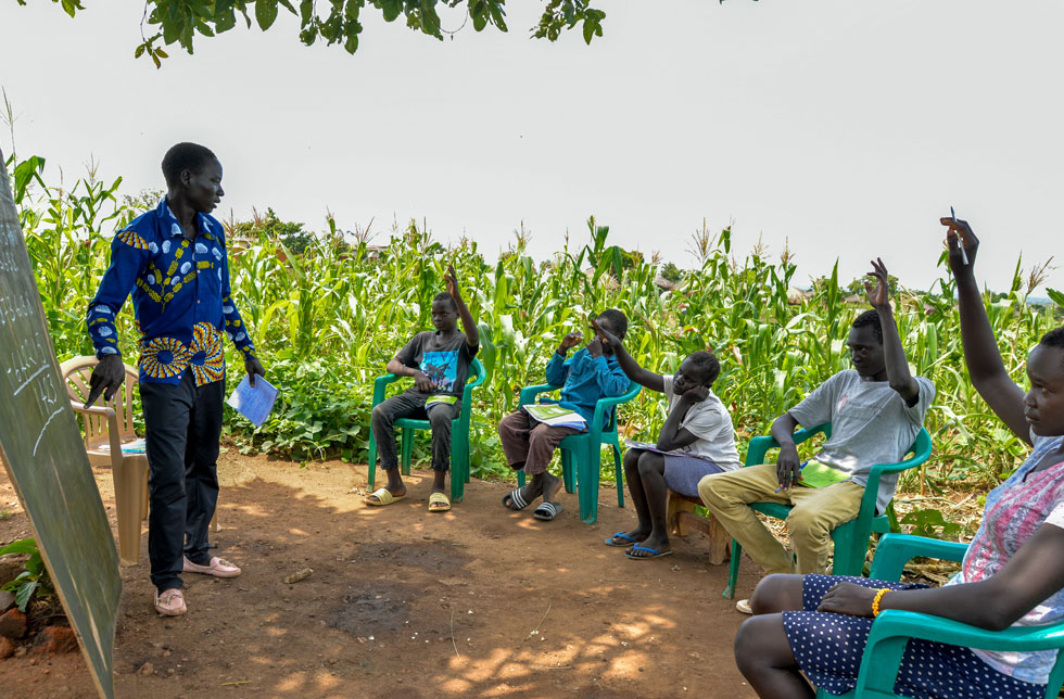 Uganda: Ein Lehrer halt eine Schulstunde im Maisfeld.