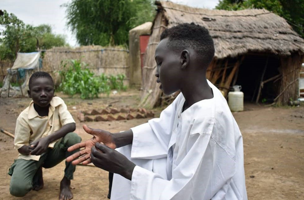 Sudan: Ein Junge erklärt seinen Freunden, wie man sich die Hände wäscht.
