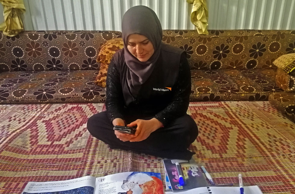 Jordanien: Eine Mitarbeiterin von World Vision bereitet Hausarbeiten via Mobiltelefon vor.