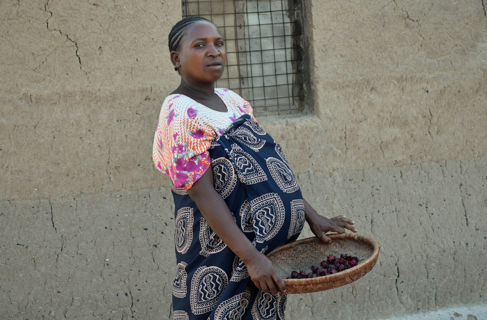 Tansania: Eine schwangere Frau hält eine Schale mit Nüssen in den Händen.